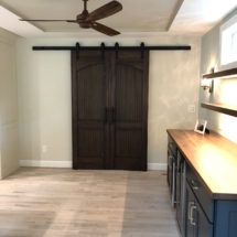 Going nuts with walnut: custom barn doors, floating shelves, and counter atop blue bar cabinets