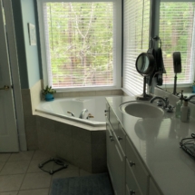 BEFORE - A corner whirlpool tub closes off the space
